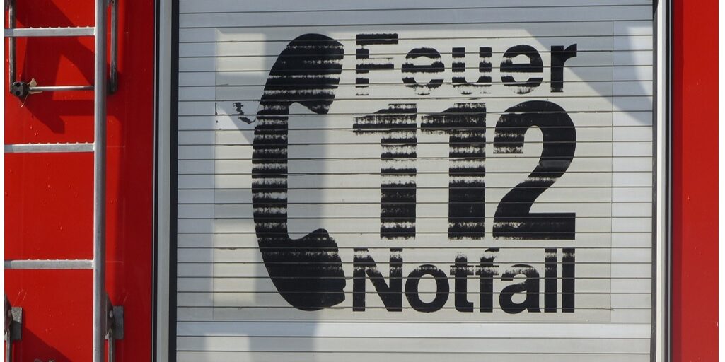 Eine rote Feuerwehrautotür mit einem großen schwarzen Telefonsymbol und dem deutschen Text „Feuer Notfall 112“, was auf die Notrufnummer der Feuerwehr 112 hinweist. - RUF Beratung - Ihre Contact Center Berater