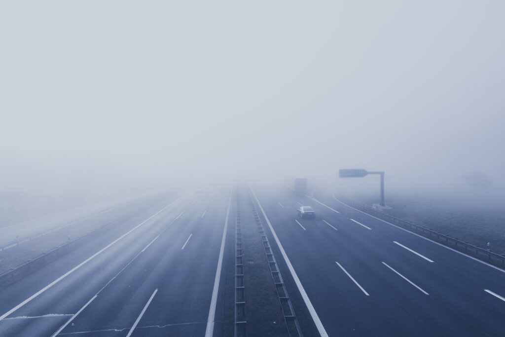 Eine neblige Autobahnszene symbolisiert die frühen Phasen der Customer Journey Awareness. Mehrere Autos und ein LKW navigieren durch mehrere Fahrspuren. Aufgrund des dichten Nebels ist die Sicht schlecht und in der Ferne sind die Verkehrsschilder kaum zu erkennen. - RUF Beratung - Ihre Contact Center Berater