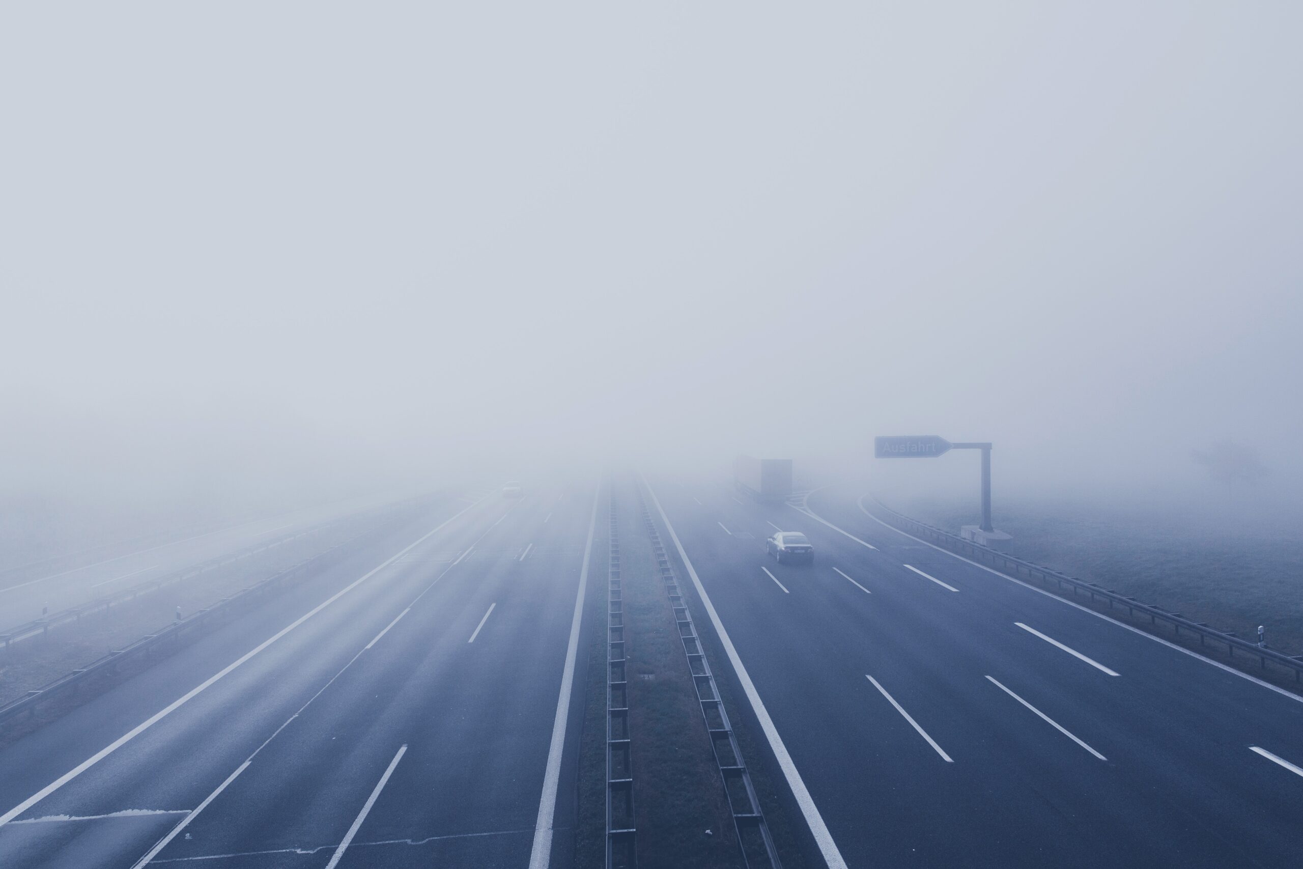 Eine neblige Autobahnszene symbolisiert die frühen Phasen der Customer Journey Awareness. Mehrere Autos und ein LKW navigieren durch mehrere Fahrspuren. Aufgrund des dichten Nebels ist die Sicht schlecht und in der Ferne sind die Verkehrsschilder kaum zu erkennen. - RUF Beratung - Ihre Contact Center Berater